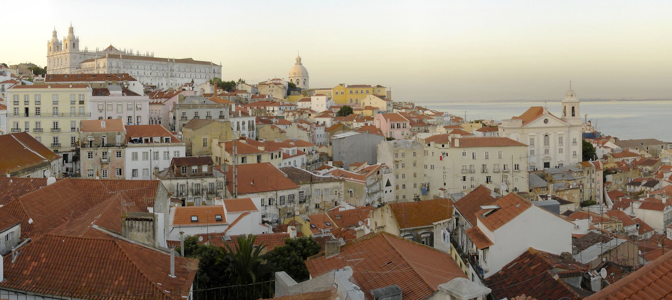 Vicolo acciottolato e ripido del quartiere di Alfama tra facciate di azulejos
