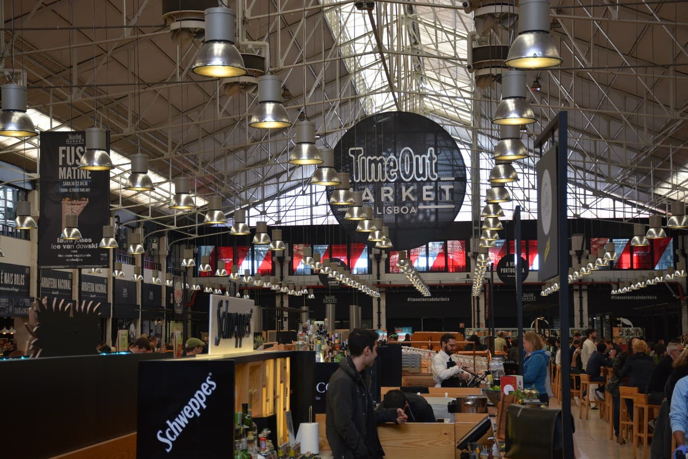 Visitantes com bebidas nas mesas comunitárias do food court do Time Out Market de Lisboa