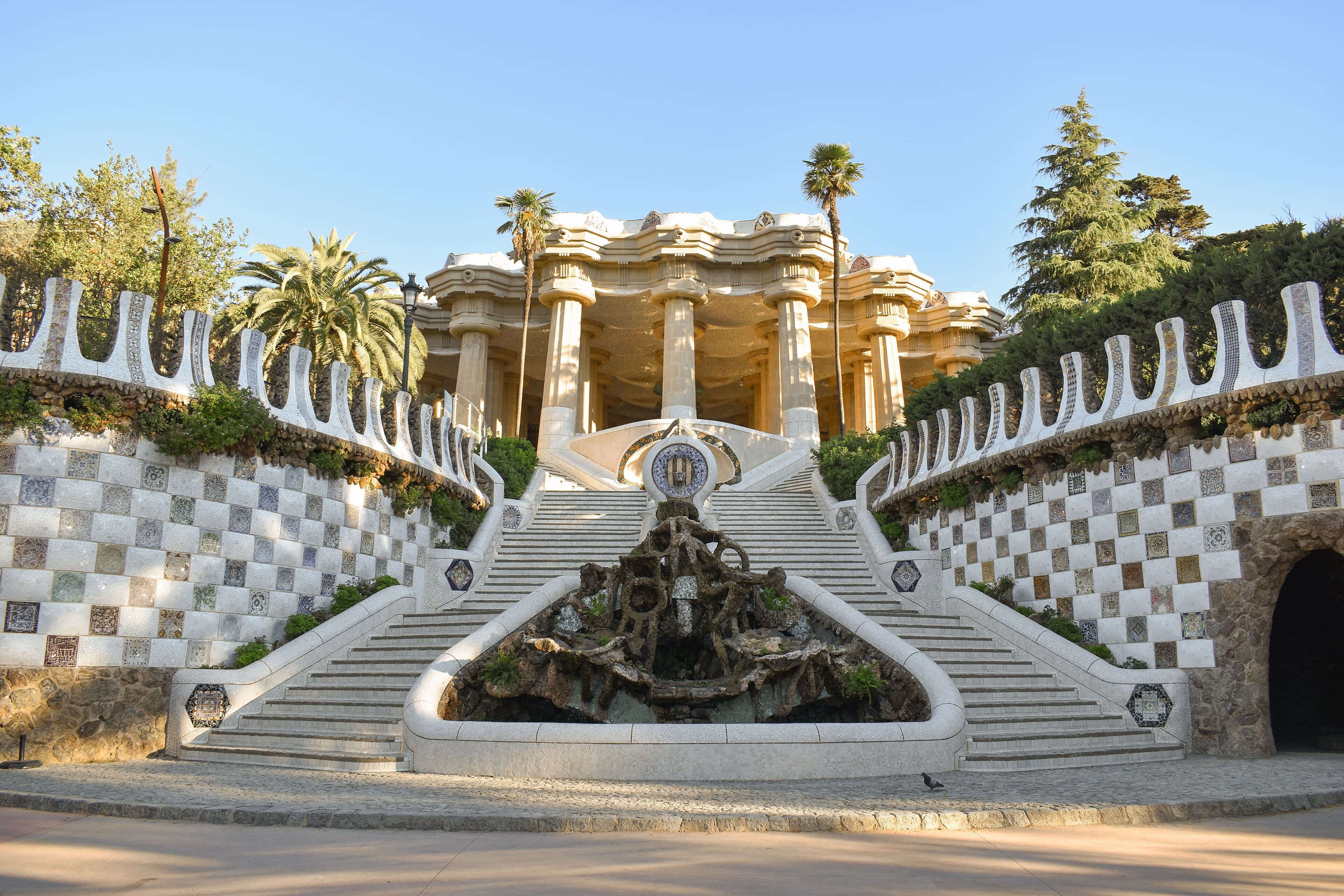 Los pabellones de cuento del Park Güell con sus tejados ondulados de trencadís y la escalinata del dragón, con la ciudad de Barcelona al fondo